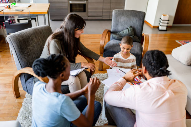 A social worker engages in a family meeting with parents and their child, discussing important documents in a cozy home setting.