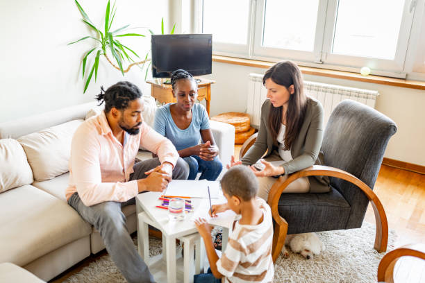 A family consults with a financial advisor in their living room while their child plays nearby.