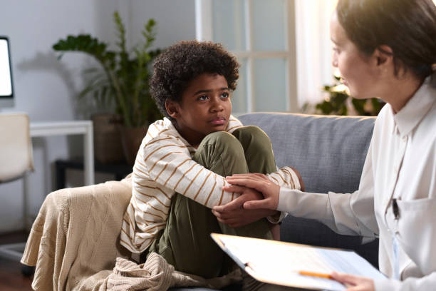 Portrait of young African American boy listening to caring psychologist in therapy session for children, copy space